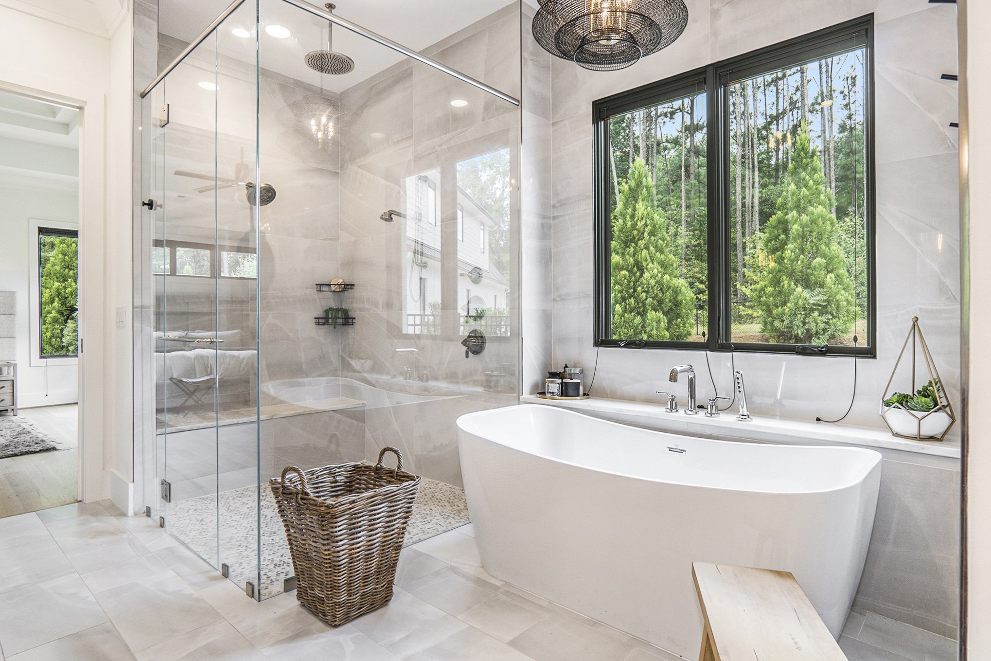 Airy primary bathroom with a freestanding tub, glass shower, and black-framed garden windows