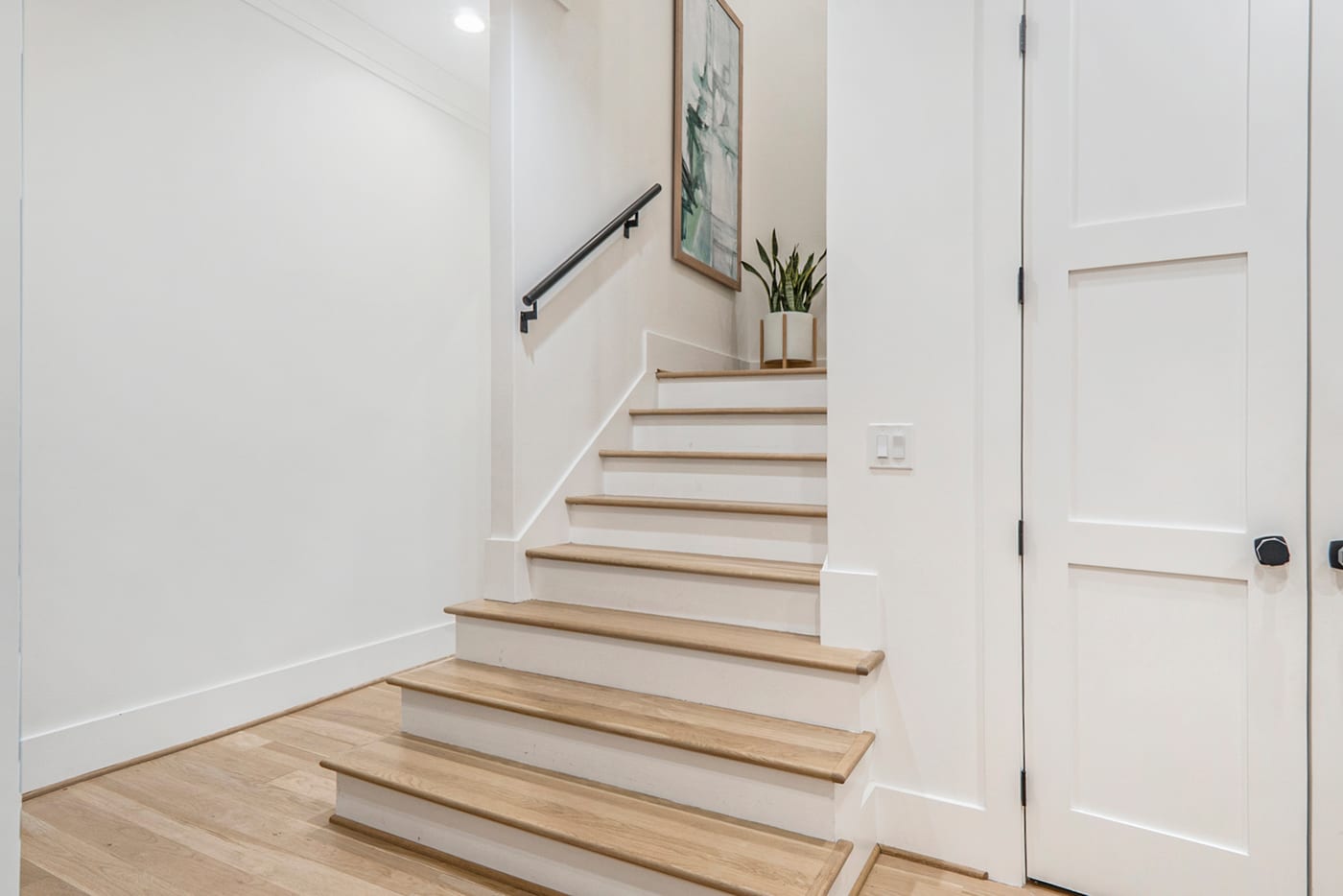 Light oak stair treads and white risers in a bright entry